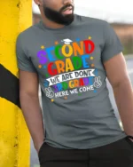 2nd Grade Done 3rd Grade Here We Come T-Shirt - model in grey shirt leaning against column