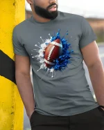 Splash Football Art Cool Sports Fan Game Day T-Shirt - model wearing grey tee, leaning on column