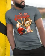 ’Tis The Season Baseball Fan Funny T-Shirt - model leaning on yellow-black pole, wearing Gray T-shirt, hand in pocket