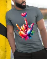 Colorful ASL I Love You Hand Sign T-Shirt Vibrant Heart Art - model wearing grey tee, leaning on column