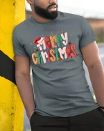 Merry Christmas Festive Typography Graphic T Shirt Cozy Holiday Tee - model wearing grey tee, leaning on column