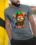 Cute Christmas Elf Dog Graphic Tee With Playful Holiday Charm - model wearing grey tee, leaning on column