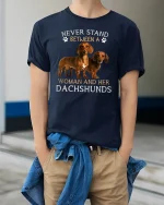 Never Stand Between A Woman And Her Dachshunds Tee Tshirt - model wearing navy tee with hands in pockets