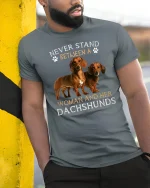 Never Stand Between A Woman And Her Dachshunds Tee Tshirt - model wearing grey tee, leaning on column