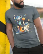 Astronaut Letter I Space Graphic Tee With Cute Cosmic Art - model wearing grey tee, leaning on column