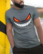 Evil Smile Red Eyes Monster Face Graphic T-Shirt - model wearing grey tee, leaning on column