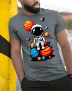Cute Astronaut Sitting on Planets T-Shirt Space Graphic Tee - model wearing grey tee, leaning on column