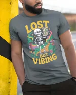 Lost But Vibing Funny Skeleton Retro Adventure Graphic T-Shirt - model wearing grey tee, leaning on column