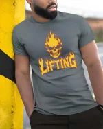 Flaming Skull Lifting Gym Dark Fitness Graphic T-Shirt Tee - model wearing grey tee, leaning on column