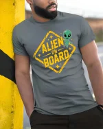 Funny Alien On Board Road Sign Graphic t-shirt Gift Idea - model wearing grey tee, leaning on column