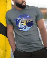 Marlin Fishing Sunset Graphic t-shirt Deep Sea Angler Tee - model wearing grey tee, leaning on column