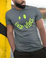 Good Vibes Graffiti Smile Graphic t-shirt Positive Tee - model wearing grey tee, leaning on column