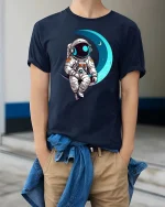 Astronaut Sitting On Moon Cute Space Graphic T-Shirt Design - model wearing navy tee with hands in pockets
