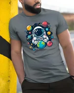 Cute Astronaut Holding Earth Space Cartoon Graphic Tshirt - model wearing grey tee, leaning on column